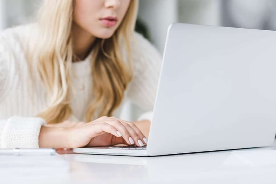 girl with blonde hair working on a laptop busy outsourcing social media